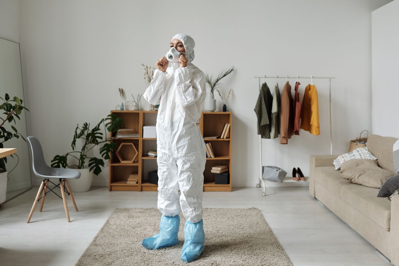 about-us Woman in protective suit wearing face mask indoors with modern interior design.