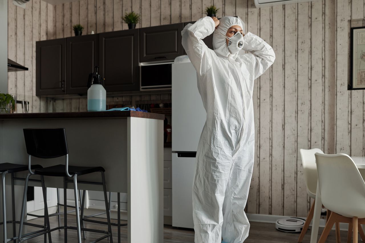 services-06 Individual in protective gear standing in a contemporary kitchen setting during the day.